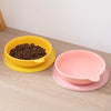 A yellow silicone pet feeding bowl filled with dark kibble rests on a matching yellow saucer.