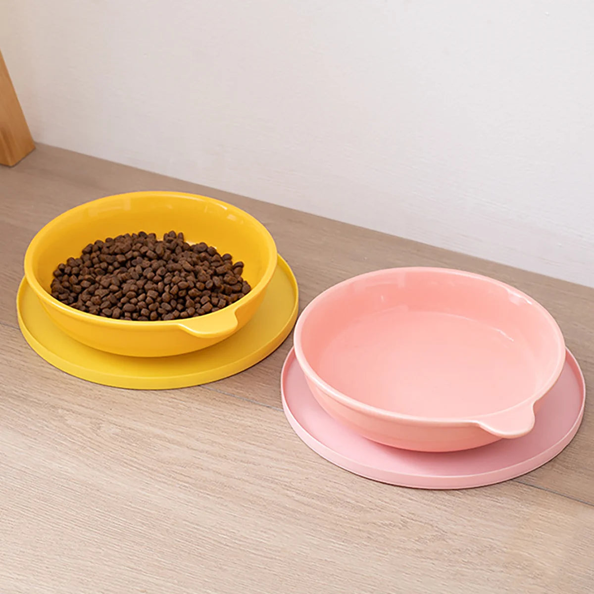 A yellow silicone pet feeding bowl filled with dark kibble rests on a matching yellow saucer.