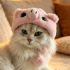 A white cat wearing a pink bear cap pet head cover