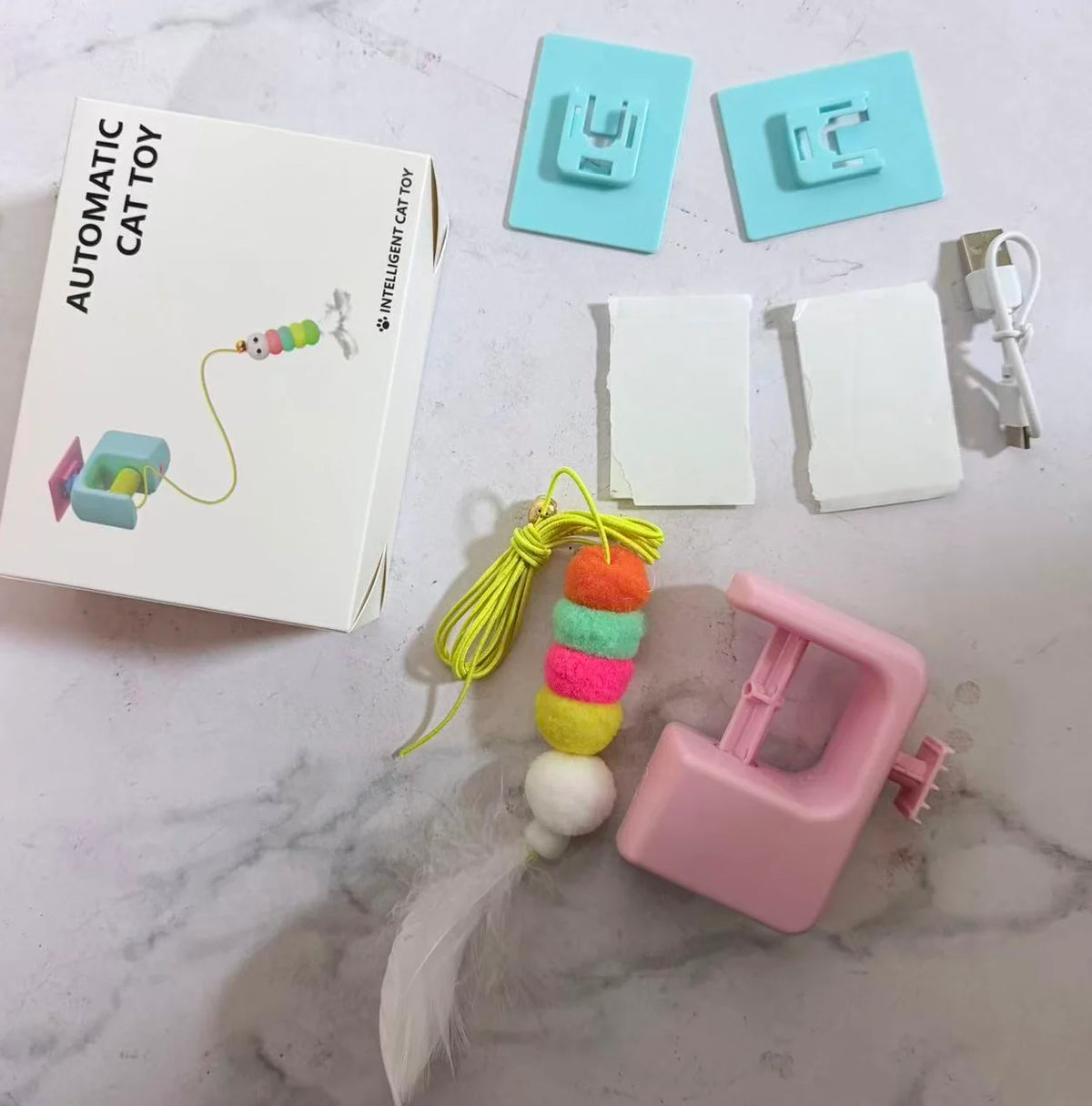 Automatisches elektrisches aufgehängtes Katzenspielzeug mit Schnur, Silikonkomponenten und rosa Kunststoffhaken.