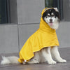 A fluffy dog wearing a bright yellow waterproof raincoat outdoors.