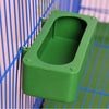A green plastic bird cage seed catcher skirt with a rectangular opening is shown against a blue wire mesh background.