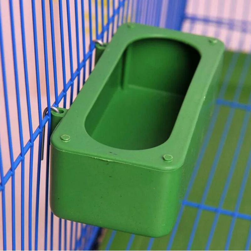 A green plastic bird cage seed catcher skirt with a rectangular opening is shown against a blue wire mesh background.