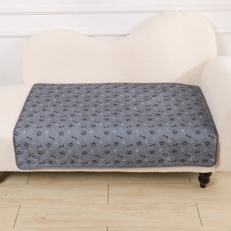 A gray pet pee pad is placed on a cream-colored upholstered surface.