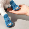 A hand holds a pair of blue breathable mesh dog shoes for summer protection.