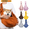 A person is holding an orange adjustable crossbody dog sling carrier with various colored fabric options.