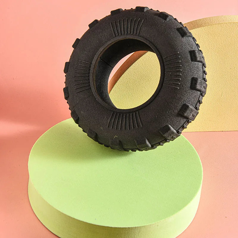 A black durable rubber chew toy with a circular opening rests on a light green stand.