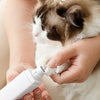 A person is using a white pet nail grinder on a cat's paw while it is sleeping.