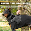 A black dog wearing a military class rubber handle control harness while being held by a person in camouflage clothing.