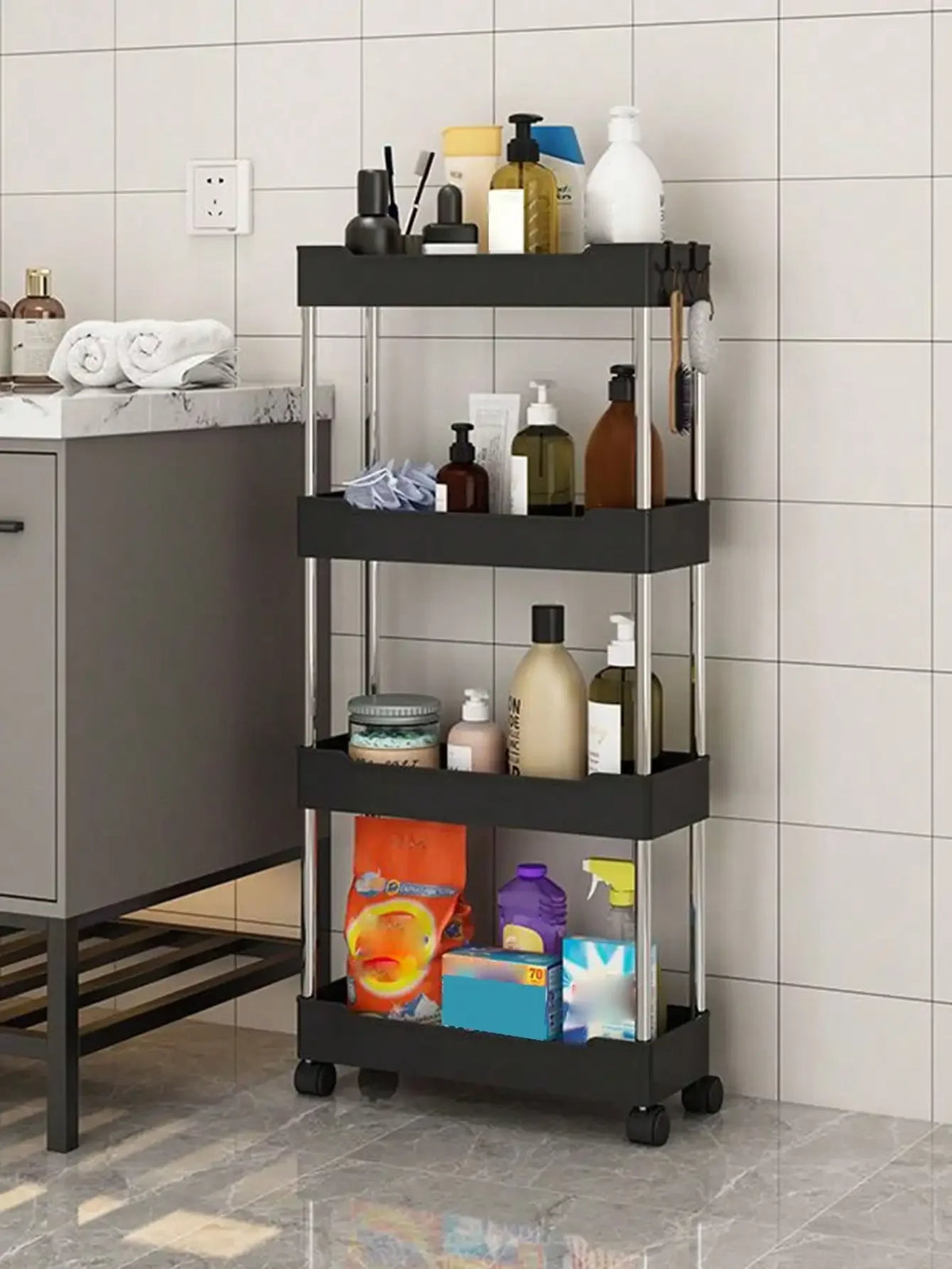 A black mobile storage rack with three tiers holding various bottles and toiletries against a white tiled wall.