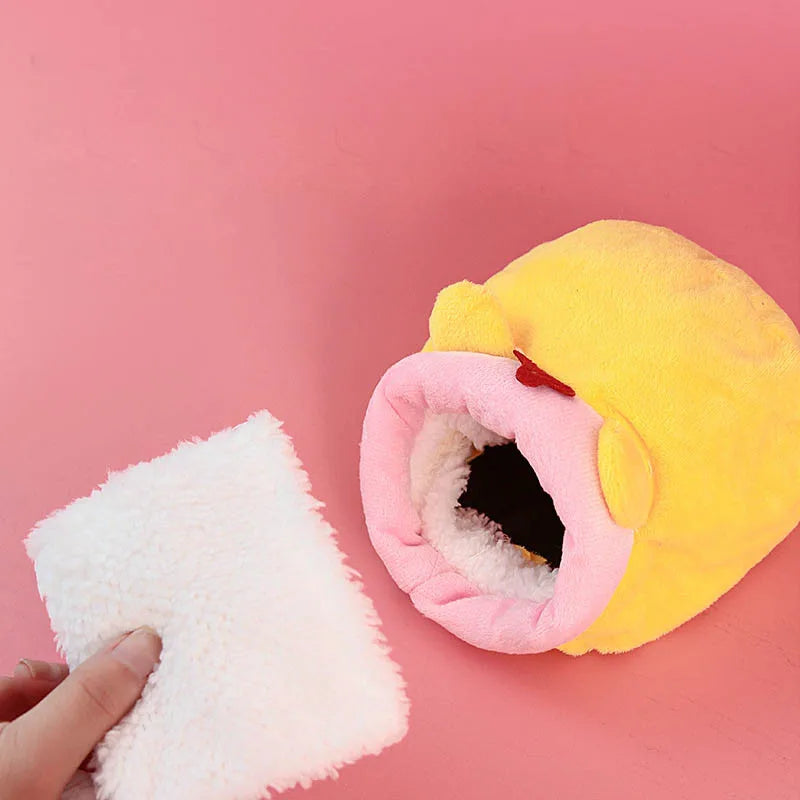 A yellow plush hamster sleeping nest with a pink opening, next to a white fluffy piece.