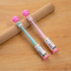 A pink silicone pet toothbrush with a soft brush head is shown resting on a wooden surface.