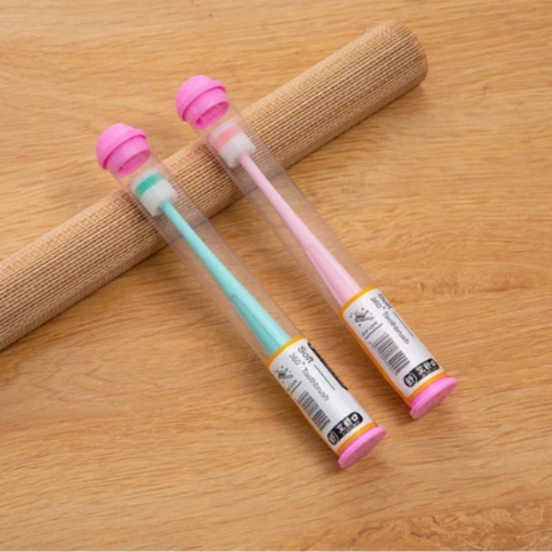 A pink silicone pet toothbrush with a soft brush head is shown resting on a wooden surface.