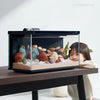 Un aquarium intelligent noir est exposé sur une table en bois, avec des poissons colorés et des éléments décoratifs.