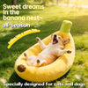 A golden yellow banana-shaped plush pet bed with a green accent is shown outdoors on green grass.