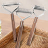 A set of double-sided grooming combs and brushes with wooden handles resting in a woven basket.