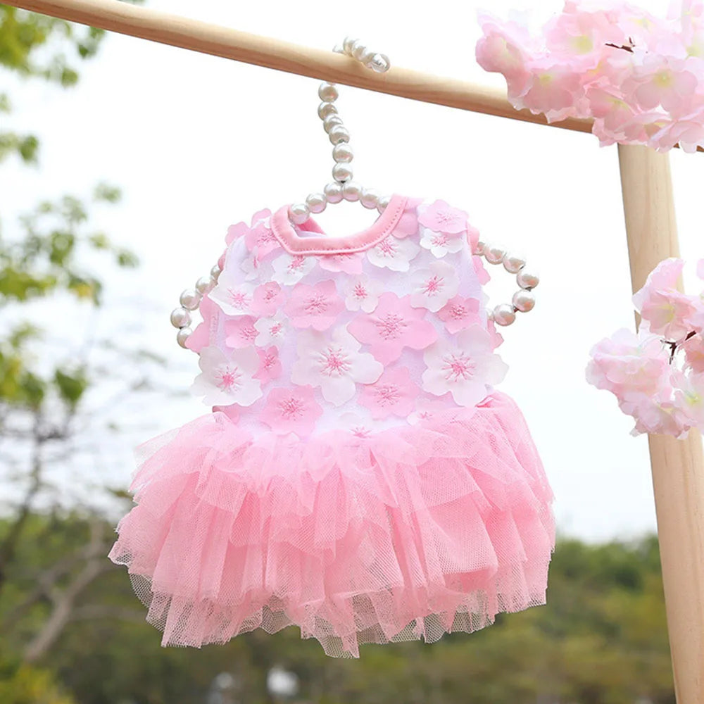 Vestido de encaje de gasa rosa para perros y gatos colgado en un marco de madera