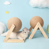 A fluffy gray kitten is resting on a wooden base with a sisal rope ball for scratching.