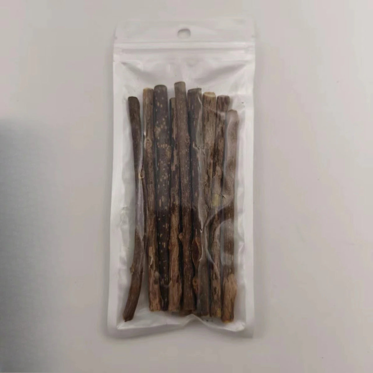 A clear plastic bag contains several natural herbal cat chew sticks.