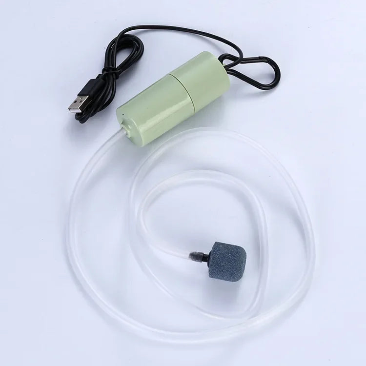 A portable USB aquarium air pump with a black cord and clear tubing is shown against a white background.