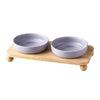 A pair of light purple ceramic cat and dog bowls resting on a wooden stand.