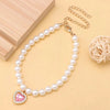 Un délicat collier de perles avec un pendentif de pierre rose, exposé sur un fond clair.