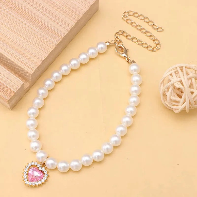 Un délicat collier de perles avec un pendentif de pierre rose, exposé sur un fond clair.