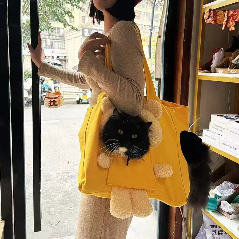 A person is holding a yellow breathable mesh pet carrier backpack with a fluffy cat inside, standing in a doorway.