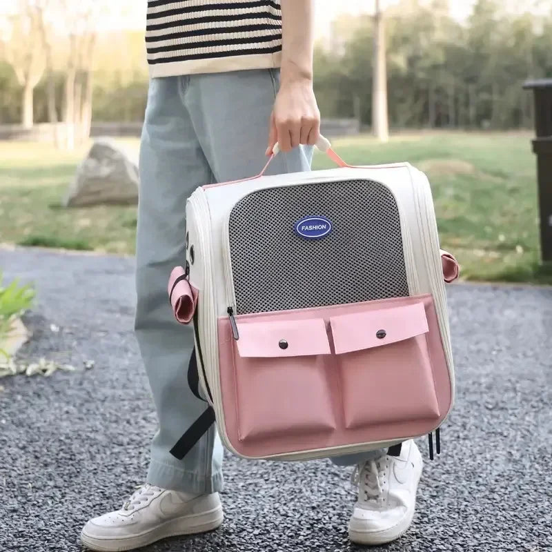 A person is holding a pink and white ventilated cat carrier backpack with adjustable straps outdoors.