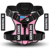A pink and black harness for a service dog is shown with training labels.