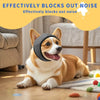 A happy dog wearing a black noise reduction ear muff lies on a wooden floor.