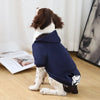 A brown and white dog wearing a navy blue cozy fleece sweatshirt with a hood and pocket.