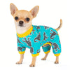A small fawn-colored dog wearing a teal pajama top with a black silhouette pattern.