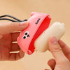 A hand holds a pink reusable pet hair roller with a cute cartoon design against a light background.