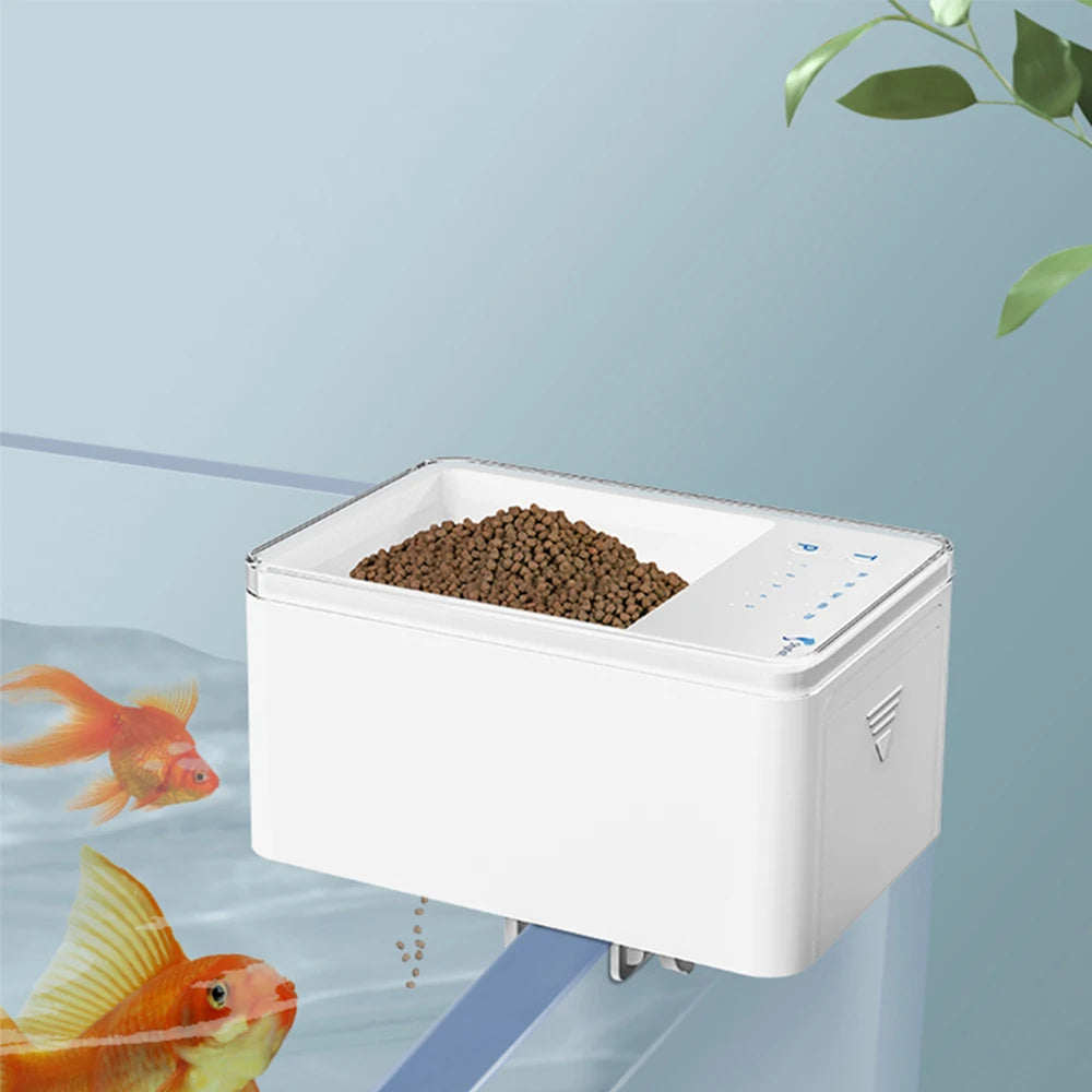 Mangeur automatique WiFi blanc pour poissons d'aquarium, avec des poissons à proximité.