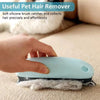 A hand is using a light blue pet hair remover brush to clean pet hair from a surface.