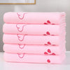 A stack of pink ultra-soft quick-dry pet bath towels with a heart design on the sleeve.