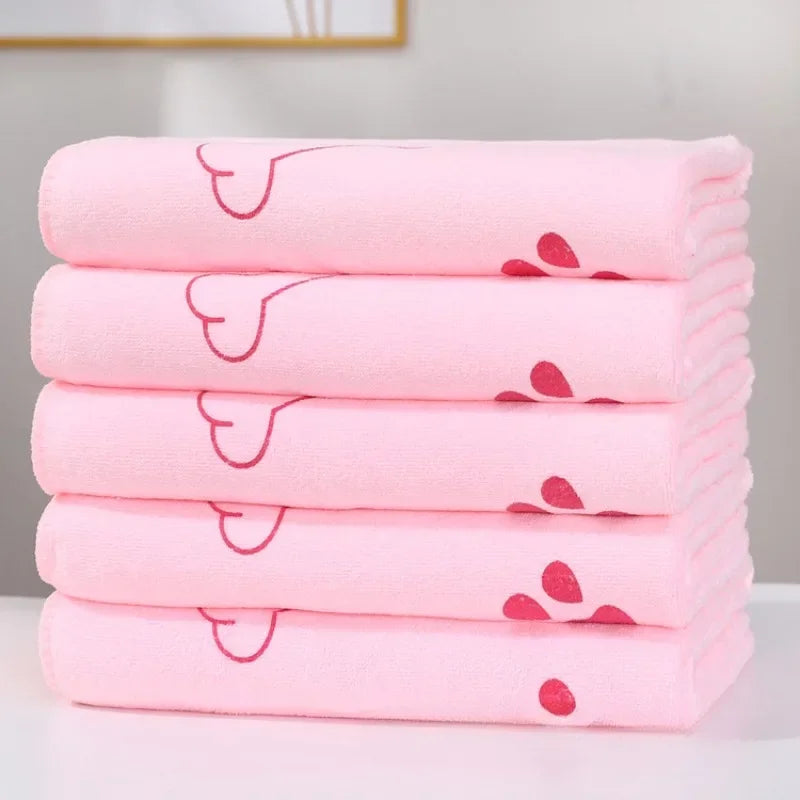 A stack of pink ultra-soft quick-dry pet bath towels with a heart design on the sleeve.
