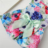 Lightweight summer skirt featuring a floral print with pink, blue, and red flowers and a pale green ribbon bow.