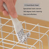 Une main utilise une tête de brosse en V pour nettoyer la grille d'une cage d'animal sur un rack de fils.