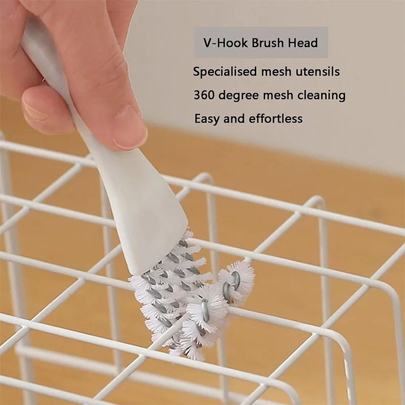 Une main utilise une tête de brosse en V pour nettoyer la grille d'une cage d'animal sur un rack de fils.