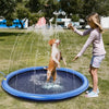 A dog is being sprayed by a water fountain from an inflatable splash pad mat in a grassy outdoor setting.