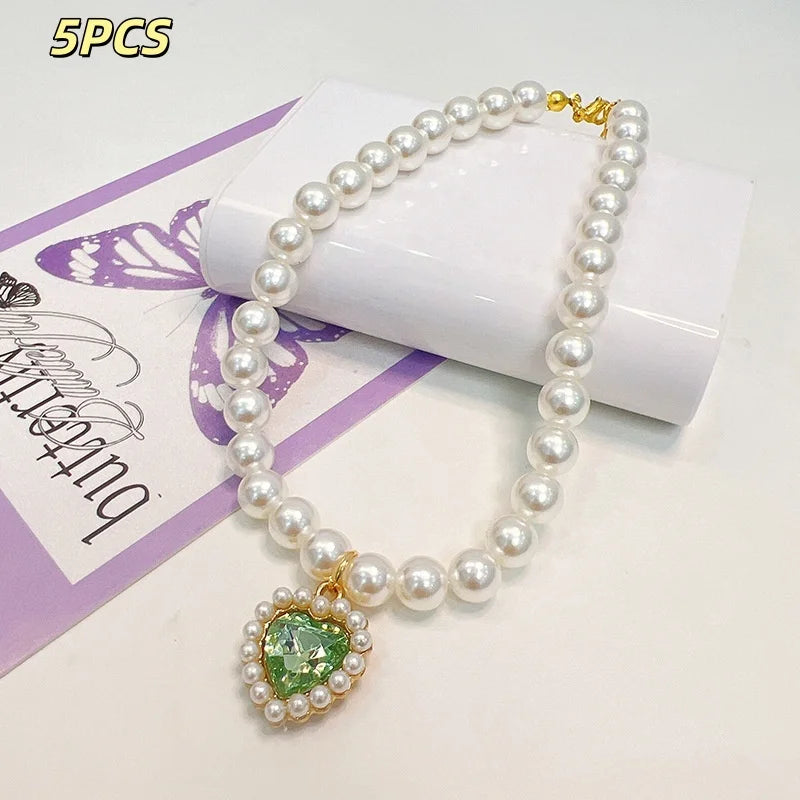 Five pieces of a pearl necklace with a green gemstone pendant displayed on a white box.