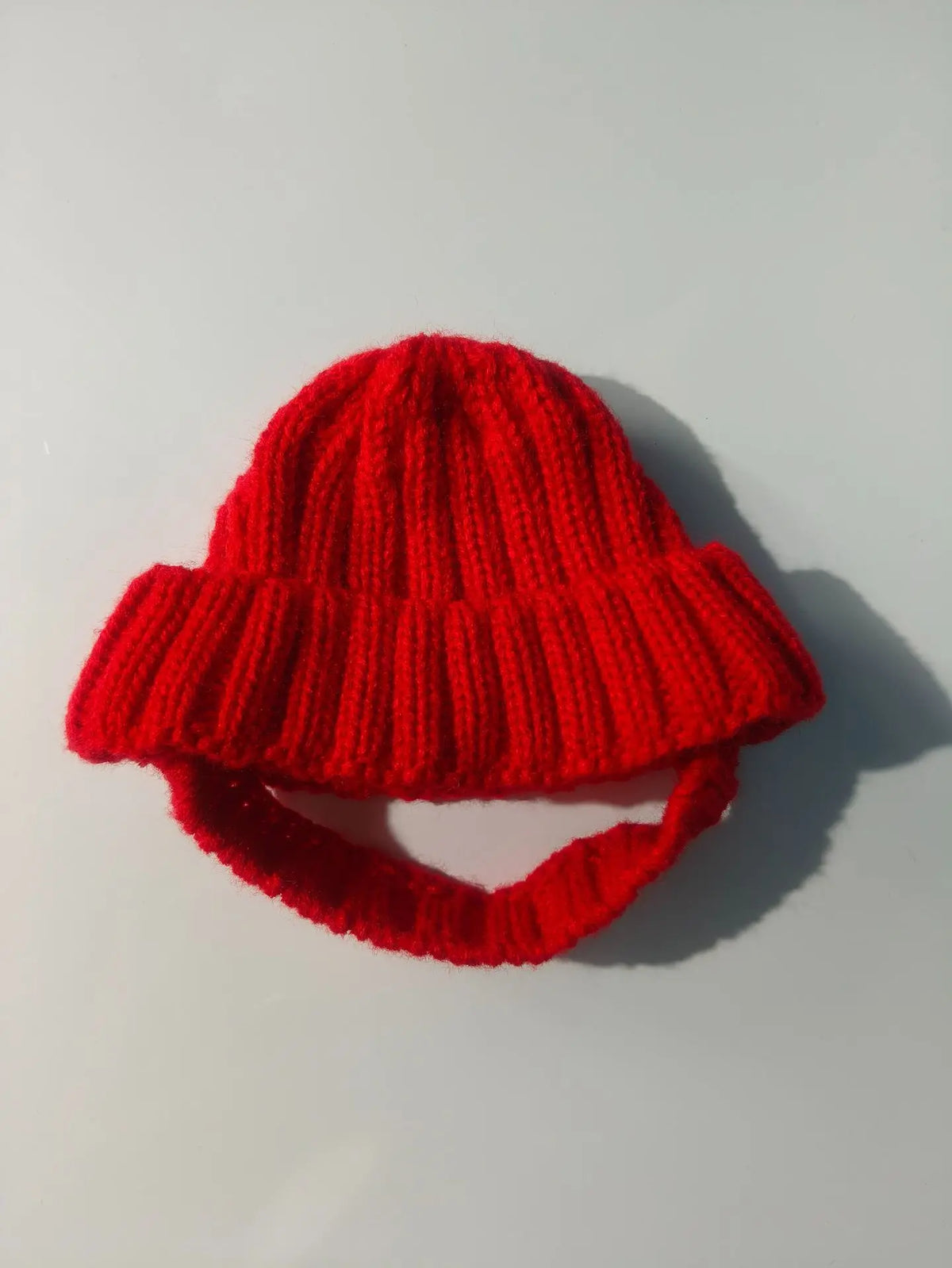 A bright red, chunky knit beanie hat designed for small dogs.