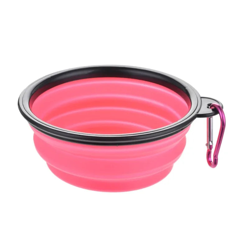 A bright pink collapsible silicone pet travel bowl with a black rim and metal clip.