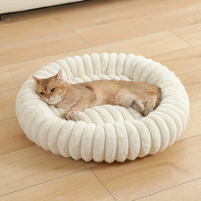 A fluffy orange tabby cat is resting inside a round, white, plush pet bed.