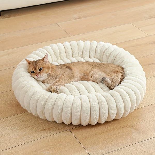 A fluffy orange tabby cat is resting inside a round, white, plush pet bed.