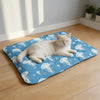 A fluffy white cat is relaxing on a blue pet mat decorated with white jellyfish patterns.