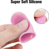 A pink silicone pet toothbrush is shown being held by a hand, with a close-up view of the bristles.