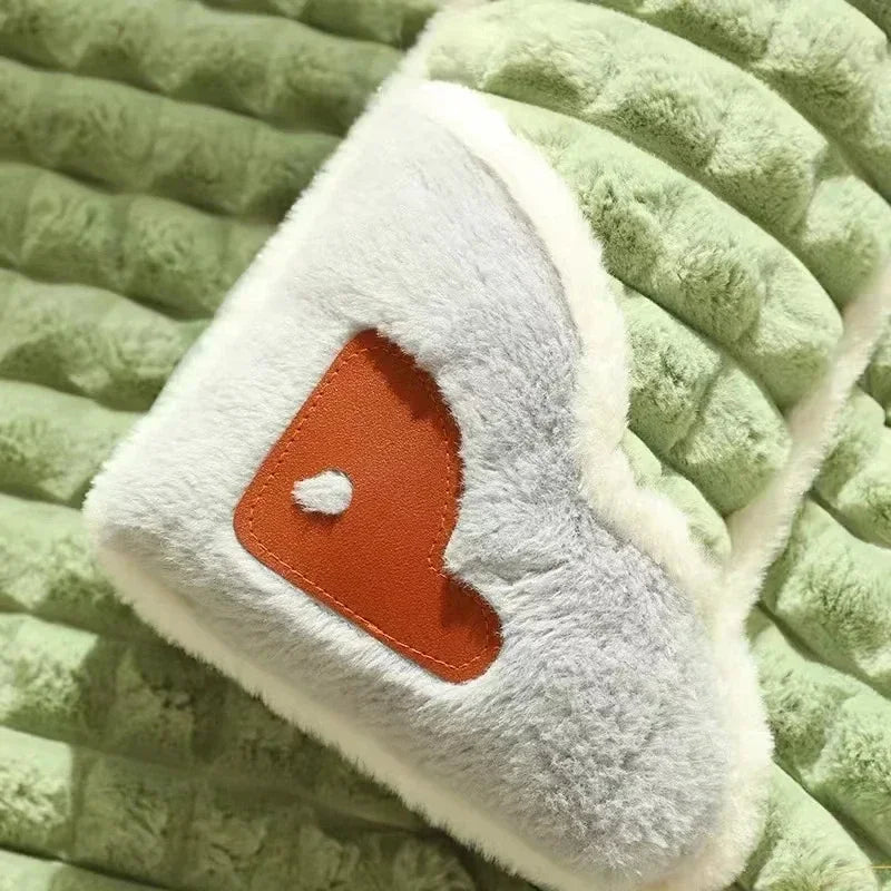 A light gray orthopedic memory foam dog bed with an orange heart design resting on a green textured surface.